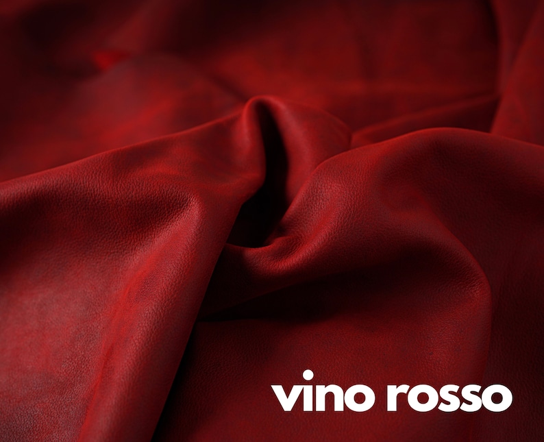 May include: Close-up of a deep red leather fabric with a textured surface. The fabric is folded and draped, creating soft folds and curves. The text "vino rosso" is printed in white at the bottom of the image.