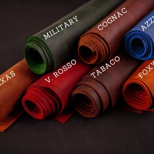 May include: Close-up of rolled leather samples in various colors, including brown, red, green, blue, and orange. The leather is labeled with names like "Texas", "V. Rosso", "Military", "Cognac", "Tabaco", "Foxy B", and "Azzurro".