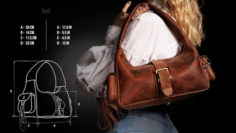 Puede incluir: Un bolso de hombro de cuero marr&oacute;n con cierre de hebilla y un peque&ntilde;o bolsillo lateral. El bolso mide 30 cm de ancho, 14 cm de alto y 33 cm de profundidad.