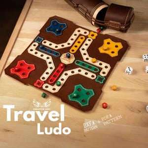Könnte beinhalten: Ein Ludo-Brettspiel aus braunem Filz mit farbigen Akzenten, Würfeln und einer Ledertasche. Das Spielbrett hat rote, blaue, grüne und gelbe Spielsteine. Der Text "Travel Ludo" ist abgebildet.
