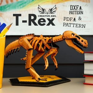 May include: A leather T-Rex dinosaur skeleton model kit. The model is assembled and is a light brown color. The model is on a hexagonal base. The background includes a white board with the text "DXF PATTERN" and "PDF PATTERN".