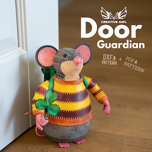 Può includere: Un fermaporta in pelle a forma di topo con testa grigia, orecchie e naso rosa e un maglione a righe gialle e bordeaux. Il topo tiene in mano un trifoglio verde, con il testo Creative Awl Door Guardian DXF & PDF Pattern scritto sopra.