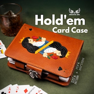 Może przedstawiać: Brązowe skórzane etui na karty Hold'em z motywem Królowej Pik. Etui jest zamykane metalową klamrą i ma napis "Hold'em Card Case". Karty do gry i szklanka whisky w tle.