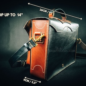 May include: A handcrafted leather messenger bag in black and brown, with white stitching and brass hardware. The bag is 14 inches wide, 10 inches tall, and 3.5 inches deep. It fits a laptop up to 14 inches. The bag has a handle and a shoulder strap.