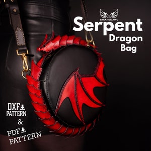 Puede incluir: Un bolso Serpent Dragon de cuero rojo y negro de forma redonda con un diseño de ala de dragón. El bolso tiene una correa y se lleva sobre el hombro.