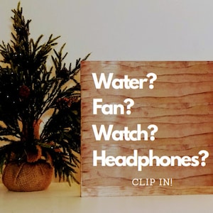 May include: A wooden sign with the text "Water? Fan? Watch? Headphones? CLIP IN!" in white letters. The sign has a wood grain pattern.