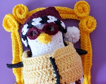 May include: A crocheted penguin wearing a hat and glasses, sitting in a yellow crocheted frame.