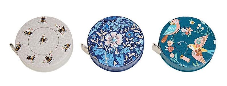 May include: Three decorative tape measures with unique designs. One features bees, another a floral pattern in blue, and the third showcases birds and flowers. Each tape measure has a silver metal pull tab.