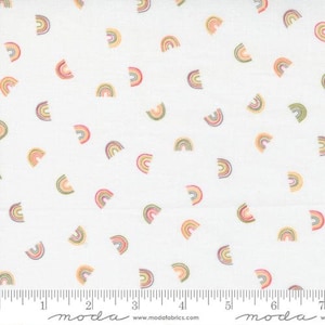 May include: White fabric with a repeating pattern of small multi-colored rainbows. The fabric has a ruler with the word "moda" printed on it.