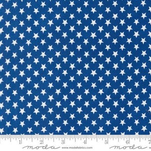 May include: Blue fabric with a white star pattern. The fabric is a solid blue color with small white stars evenly spaced throughout. The fabric is shown with a ruler for scale.