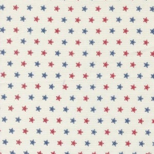 May include: Cream-colored fabric with a repeating pattern of red and blue stars. The stars are evenly spaced and outlined, creating a patriotic or Americana theme. The fabric appears to be cotton or a similar material.