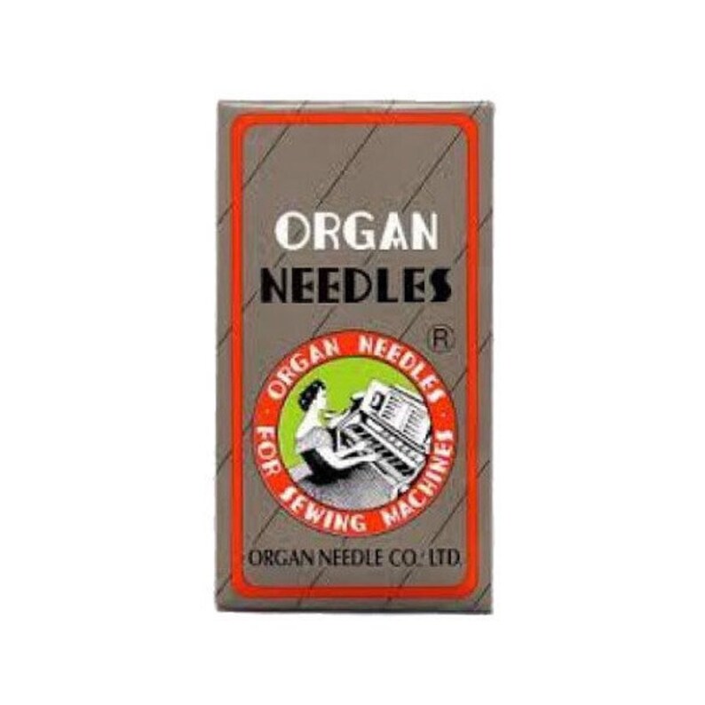 May include: A brown and orange box with the text "ORGAN NEEDLES" in white. The box has a smaller image of a woman sewing on a sewing machine with the text "ORGAN NEEDLES FOR SEWING MACHINES" around the image. The bottom of the box says "ORGAN NEEDLE CO. LTD."