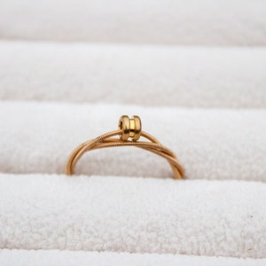 May include: A gold guitar string ring with a decorative bead in the center.