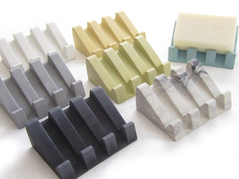 May include: Set of six soap dishes in various colors, including white, gray, black, yellow, green, and gray with white marbling. Each dish has a sloped design with four ridges to hold a bar of soap.