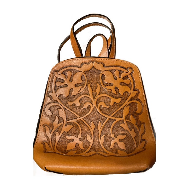 May include: A brown leather backpack with a floral design. The backpack has a top flap with a buckle closure and adjustable straps.