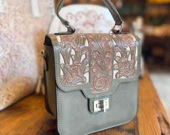 Peut inclure: Un sac à main vert sauge doté d'une poignée supérieure et d'un rabat rectangulaire avec un motif floral en relief de couleur cuivre. Le sac comprend une fermeture à loquet en métal argenté sur le devant et une silhouette structurée.