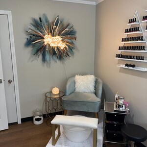 May include: Interior of a nail salon featuring a light blue armchair, foot spa, and a rolling cart with nail supplies. A neon sign reading "Yay it's nail day" is on the wall. A decorative wall hanging is also present.