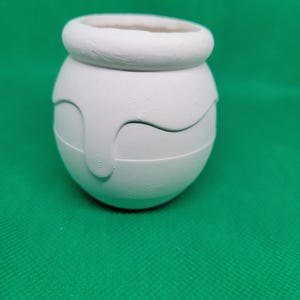 May include: A white ceramic pot with a rounded shape and a slightly raised rim. The pot has a textured surface and a drip-like design around the middle.