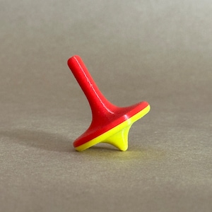 May include: A red and yellow wooden spinning top toy. The top is shaped like a cone with a rounded base.