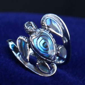 May include: A silver ring with a detailed turtle design. The turtle's shell is made of iridescent abalone shell, creating a beautiful blue and green pattern.
