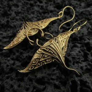 Könnte beinhalten: Ein Paar goldfarbene Ohrhänger mit einem detaillierten Manta-Rochen-Design. Die Ohrringe haben ein geometrisches Muster und hängen an einem Haken.