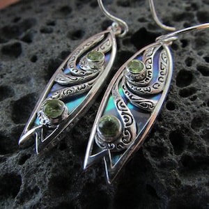 Può includere: Un paio di orecchini d'argento con pietre preziose verdi incastonate in un design a conchiglia di abalone blu e verde.