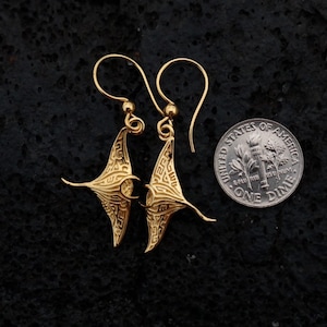 May include: Gold-tone earrings shaped like manta rays, shown next to a US dime for scale.