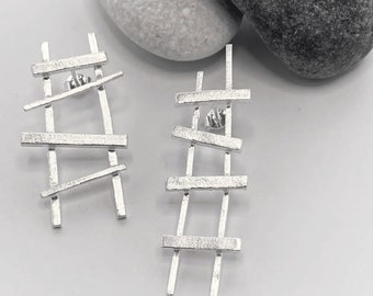 Modern and geometric mismatched silver stud earrings in 3D effect ladder design