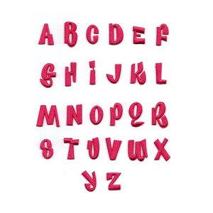 Puede incluir: Un conjunto de letras de fieltro rosa en una fuente estilizada, deletreando el alfabeto de la A a la Z.