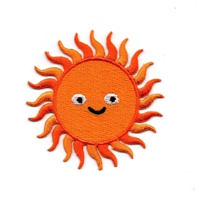 Puede incluir: Parche de hierro bordado naranja de un sol sonriente con ojos blancos y boca negra.