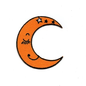 Könnte beinhalten: Orangefarbener Halbmond mit einem lächelnden Gesicht und Wimpern, mit drei weißen Sternen oben drauf.