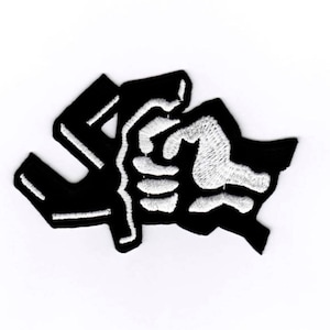May include: Black and white embroidered patch featuring a stylized fist breaking through a swastika.