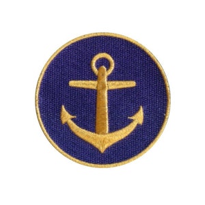 May include: A navy blue circular patch with a gold anchor design. The anchor is centered within the circle, and the patch has a gold border. The patch is likely an embroidered emblem.