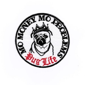 Puede incluir: Un parche redondo blanco bordado con un pug negro que lleva una corona y una cadena. El texto alrededor del pug dice "No Money No Problems" y el texto debajo del pug dice "Pug Life" en rojo.