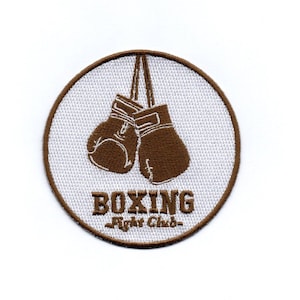 Op de afbeelding: Bruin geborduurd patch met een witte achtergrond. De patch heeft twee bruine bokshandschoenen die aan een touwtje hangen en de tekst "BOXING -Right Club-."