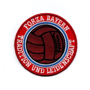 Peut inclure: Écusson rond avec un ballon de football rouge foncé. Le bord rouge porte l'inscription blanche "FORZA BAYERN" et "TRADITION UND LEIDENSCHAFT". Le ballon est entouré d'un cercle bleu et blanc sur fond blanc.