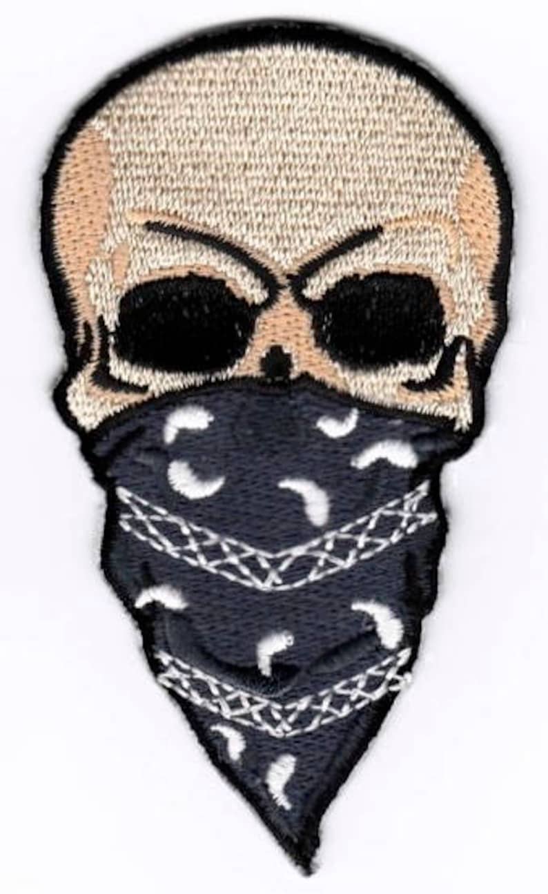 May include: Embroidered patch of a white skull wearing a black bandana with a white paisley pattern.