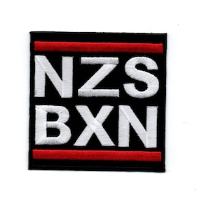 Könnte beinhalten: Schwarzer und weißer gestickter Aufnäher mit den Buchstaben "NZS BXN" in Weiß und zwei roten Streifen oben und unten.