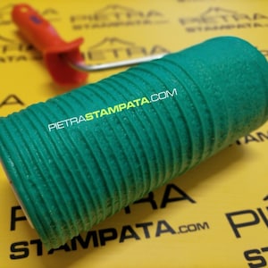 May include: Green textured paint roller with a ribbed surface. The roller is used for creating a stone-like effect on walls. The text "PIETRASTAMPATA.COM" is printed on the roller.