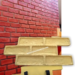 Può includere: Uno stampo per texture a muro di mattoni per creare muri di mattoni realistici. Lo stampo è realizzato in materiale beige e ha una superficie testurizzata. Lo stampo è diviso in due sezioni, con un manico su ogni sezione. Lo stampo viene utilizzato per creare un effetto a muro di mattoni su cemento o altre superfici. Lo stampo è mostrato accanto a un muro di mattoni rossi.
