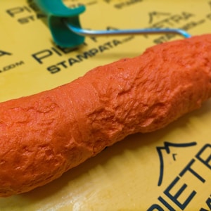 May include: Orange textured paint roller with a green handle. The roller is designed to create a stone-like effect on walls.