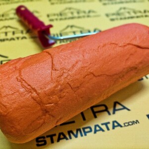 May include: Orange textured paint roller with a red handle. The roller is designed to create a stone-like finish on walls.