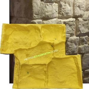 Può includere: Uno stampo in gomma giallo per creare una texture di muro in pietra. Lo stampo ha una superficie ruvida e irregolare ed è progettato per creare un effetto di muro in pietra realistico. Lo stampo è mostrato accanto a un muro che è stato creato usando lo stampo.