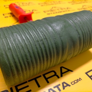 May include: A green textured paint roller with a red handle. The roller is designed to create a stone-like effect on walls.