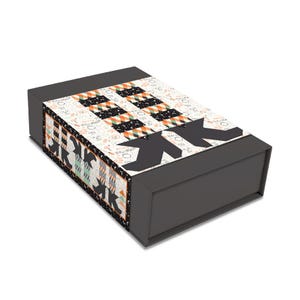 May include: A rectangular dark gray gift box featuring a decorative sleeve with a repeating pattern of black witch boots and striped orange, black, and white stockings. The background of the sleeve includes small Halloween icons and the text Happy Halloween.