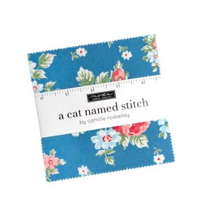May include: A stack of blue fabric squares with a floral pattern of pink and white flowers and green leaves. The fabric is labeled "a cat named stitch" by Camille Roskelley.