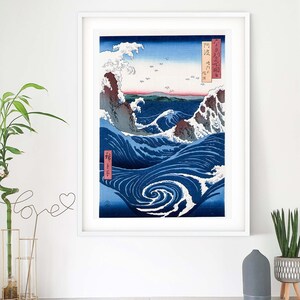 May include: A framed print of a Japanese woodblock print depicting a large wave crashing against a rocky shore. The wave is blue and white, and the shore is brown and green. The print is titled "The Great Wave off Kanagawa" in Japanese characters.
