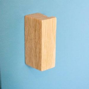 May include: A light brown wooden cabinet knob with a rectangular shape.