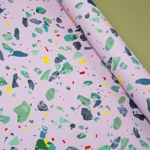May include: Pink wrapping paper with a terrazzo pattern featuring various colors including green, blue, yellow, and red.