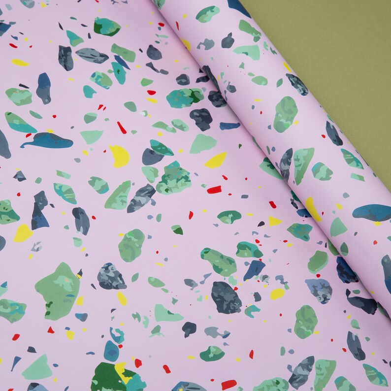 May include: Pink wrapping paper with a terrazzo pattern featuring various colors including green, blue, yellow, and red.